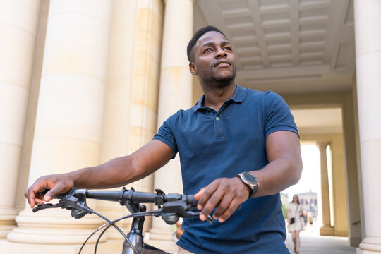Contemplative man wheeling bicycle and looking away