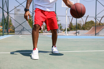 Man practicing basketball at sports court on sunny day