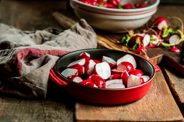 Red radishes in casserole dish at table