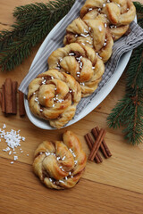 Kanelbullar, traditional swedish cinnamon and cardamon buns on wooden table with pine branche decorations