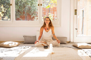 Smiling spiritual woman with rin gong and healing crystal at home