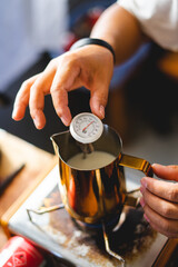 Barista boil hot milk in jar and test temperature,milk use mix in coffee make foam latte coffee