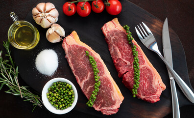 Raw fresh meat two pieces of beef steaks on wood cutting board.