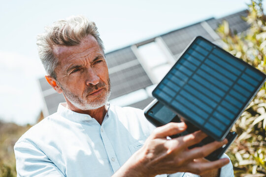 Man examining solar panel equipment on sunny day