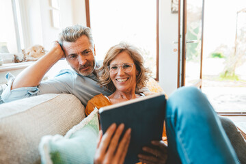 Mature couple using tablet PC sitting on sofa in living room