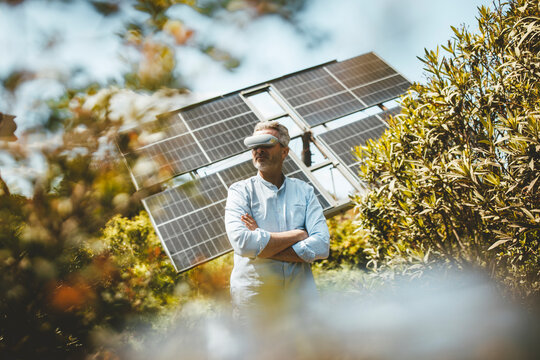 Man standing with virtual reality simulator in front of solar panels