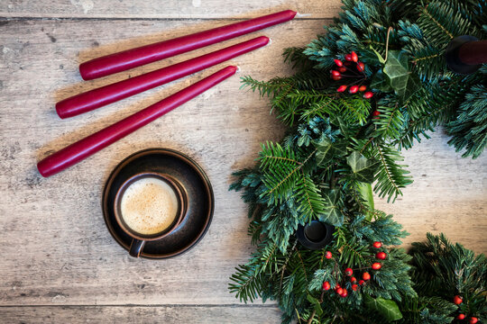 Studio shot of cup of coffee and wreath made of spruce, juniper, ivy and rose hips