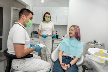 beautiful girl talking and consulting with Caucasian male dentist and assistant.