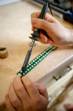 Hands of technician soldering circuit board at workshop