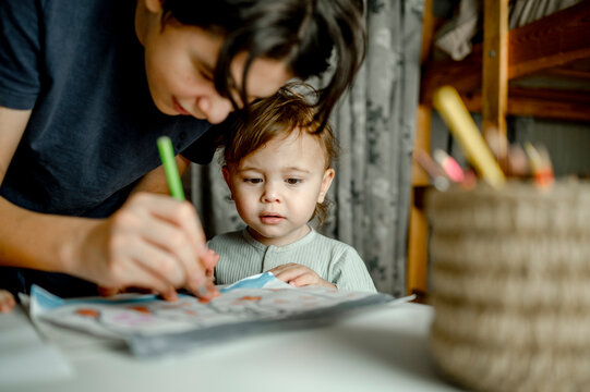 Boy teaching drawing to baby brother at home