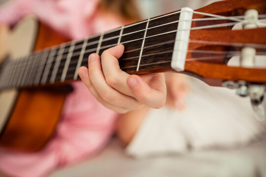 Hand of girl playing guitar at home