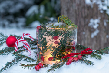 Weihnachtsdekoration mit Eislaterne mit Hagebutten und Eibenzweigen im Wintergarten