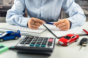 hands of a woman on a desk behind a keyboard with a small model car.