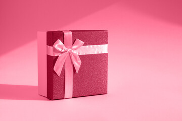 Viva magenta gift. The fashionable trending color of 2023. Tinted image of a gift box on a paper background. The concept of a holiday, birthday, Valentine's Day. Sensual romantic color in bright light