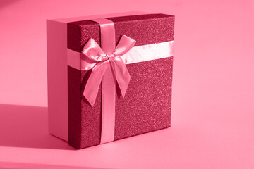 Viva magenta gift. The fashionable trending color of 2023. Tinted image of a gift box on a paper background. The concept of a holiday, birthday, Valentine's Day. Sensual romantic color in bright light