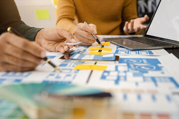 Naklejka premium UX, UI developer and ui designer brainstorming about mobile app interface wireframe design with customer breif and color code at office.
