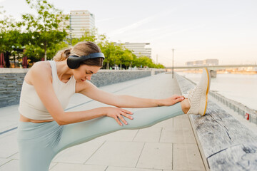 Fototapeta na wymiar Young sportswoman listening to music while doing workout at embankment
