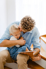 Obraz premium Young father and his daughter using tablet computer on stairs at home