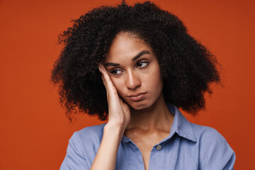 Bored afro woman touching her temple and looking aside isolated