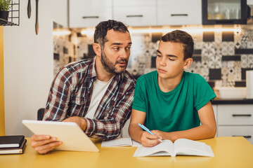 Obraz premium Father is helping his son with learning. They are doing homework together.
