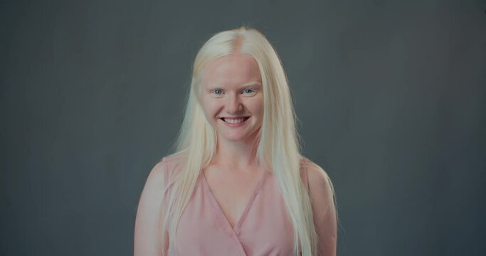 NATURAL BEAUTY Happy young albino woman, college student smiling cheerfully at camera isolated at gray background.
