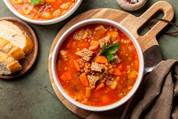 Beef Vegetable Soup with Lentils. Main ingredients are carrot, onion, cellery, potato, tomato and parsley. Green background.