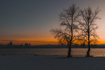 Beautiful winter view of the city of Dnipro during sunset or sunrise. Winter landscape. Ukrainian city. The lights of a sun. Calm nature copies the space background.