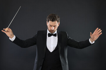 Professional conductor with baton on black background