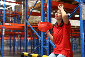 Portrait of warehouse workers young asian woman sitting and taking a break while wipe the sweat away after controlling stock and inventory in retail warehouse logistics, distribution center