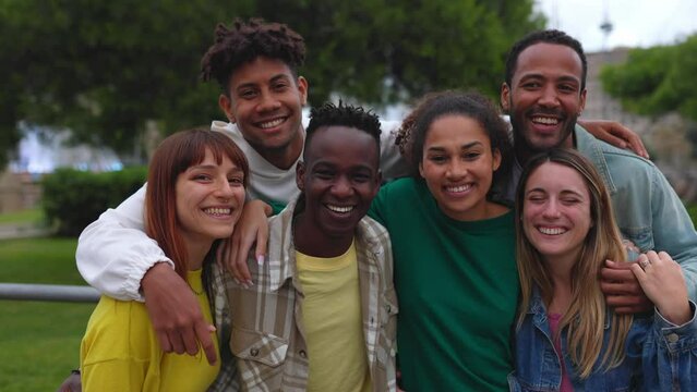 Group portrait of happy multiethnic young friends smiling at camera in city street. Urban lifestyle, community and unity people concept