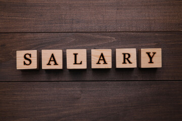 Word Salary made with cubes on wooden table, flat lay