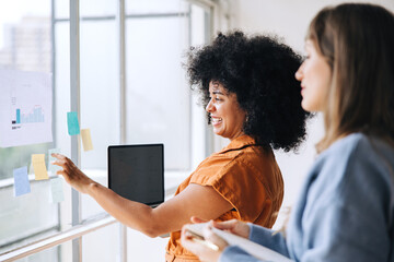Happy young businesswomen brainstorming using sticky notes