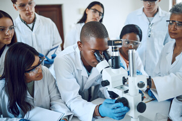 Teamwork, collaboration and group of scientists with microscope for experiment. Science, laboratory and team of people or doctors with books and equipment for medical research, analysis and testing.