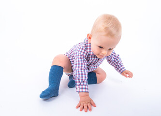 Playful beautiful baby boy wearing plaid baby clothes standing over white studio background ready to start crawling direction to his mother. Baby and play time. 