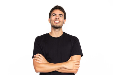 Fototapeta premium Confident young man with crossed arms. Portrait of happy Caucasian male model with short dark hair in black T-shirt looking away, smiling with proud look. Success, self-assurance concept