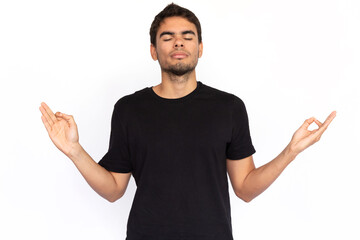 Relaxed young man with mudra gesture. Portrait of pensive Caucasian male model with short dark hair...