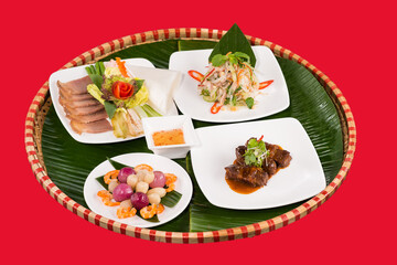 Family dinning table of Tet holiday or Lunar New Year with traditional foods: pork belly and eggs braised in coconut water, pickles, rice, Banh Tet (rice cake), fried vegetables, bitter melon soup. 