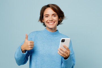 Young smiling happy caucasian woman wear knitted sweater hold in hand use mobile cell phone show...