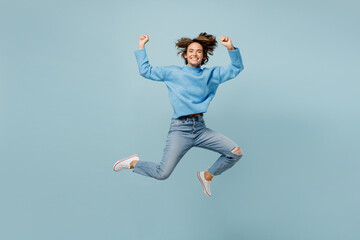 Fototapeta na wymiar Full body young fun woman wear knitted sweater look camera doing winner gesture celebrate clenching fists say yes isolated on plain pastel light blue cyan background studio. People lifestyle concept.
