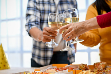 Group of diversity friends toasting and clinking glasses of wine together in the party.
