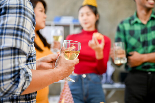 A man in corporate party, holding a glass of wine, enjoying the the party at his workplace.