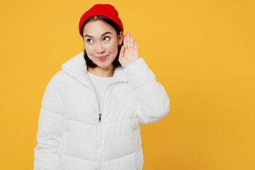 Young curious nosy fun woman of Asian ethnicity wear white padded windbreaker jacket red hat try to...