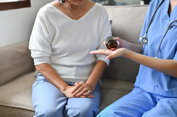 cropped image, A female nurse or caregiver giving a medicine to an elderly woman.