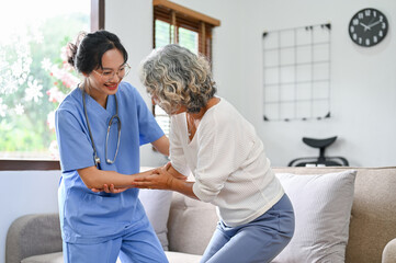 Fototapeta premium A 60-year-old elderly retire woman being helped by a young female nurse to standup and walk.
