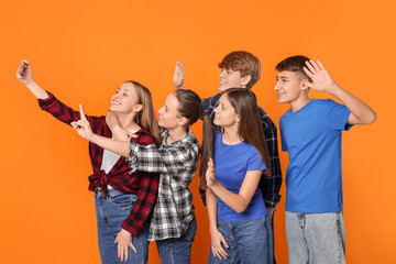 Fototapeta premium Group of happy teenagers taking selfie on orange background