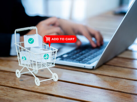 Add To Cart Icon Sign Appear On White Shopping Trolley Cart Contained Parcel Boxes With Check Marks Near The Business Person Who Using Laptop Computer, Online Shopping Client Customer Concept.