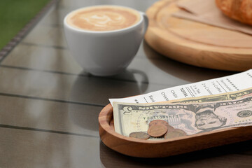 Tips, receipt and cup with coffee on wooden table, closeup - Powered by Adobe