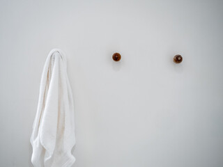 Close-up white towel hanging on a hook, hanger on white wall background in a hotel room with copy space, minimal style.