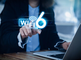 Wi-Fi 6 speed logo glowing on virtual screen while businesswoman pointing hand and using laptop...