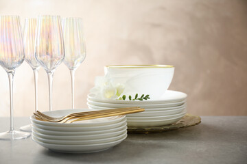 Set of glasses and dishes with flowers on light grey table